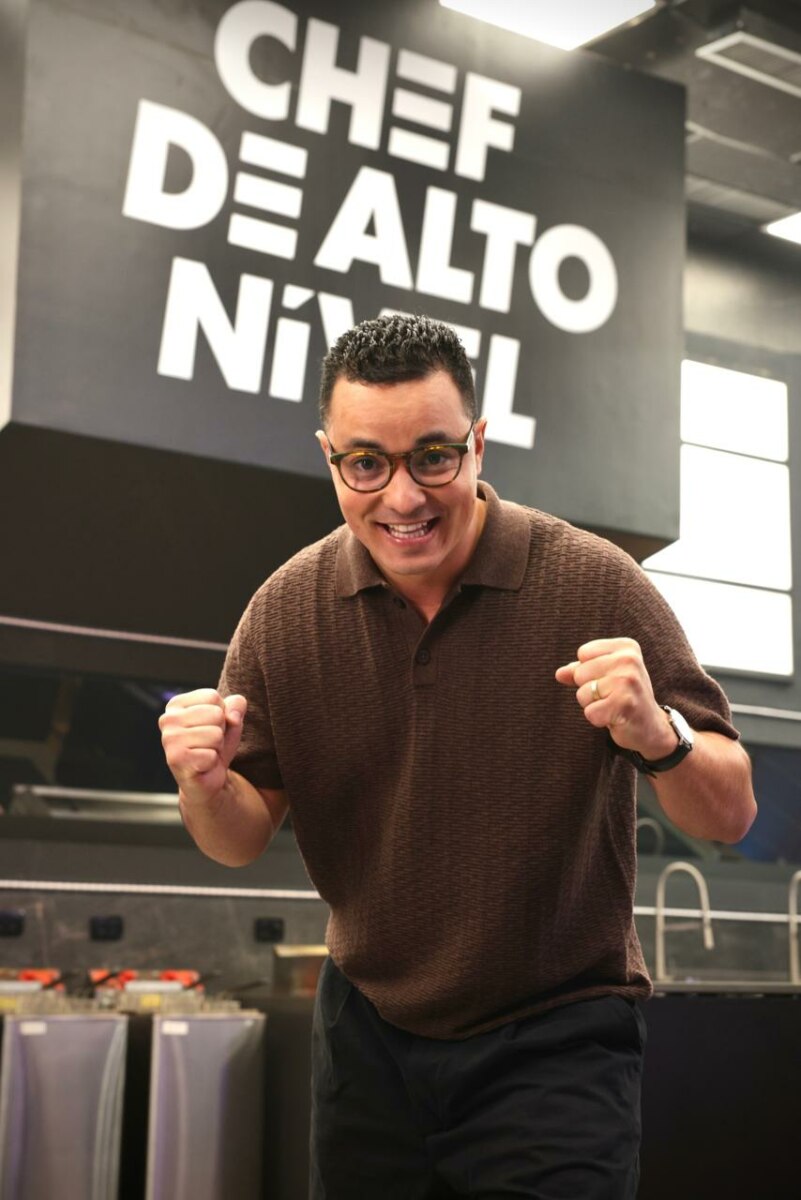 Luiz Lira comemora vitória no reality Chef de Alto Nível da TV Globo em cozinha profissional com punhos cerrados e sorriso confiante