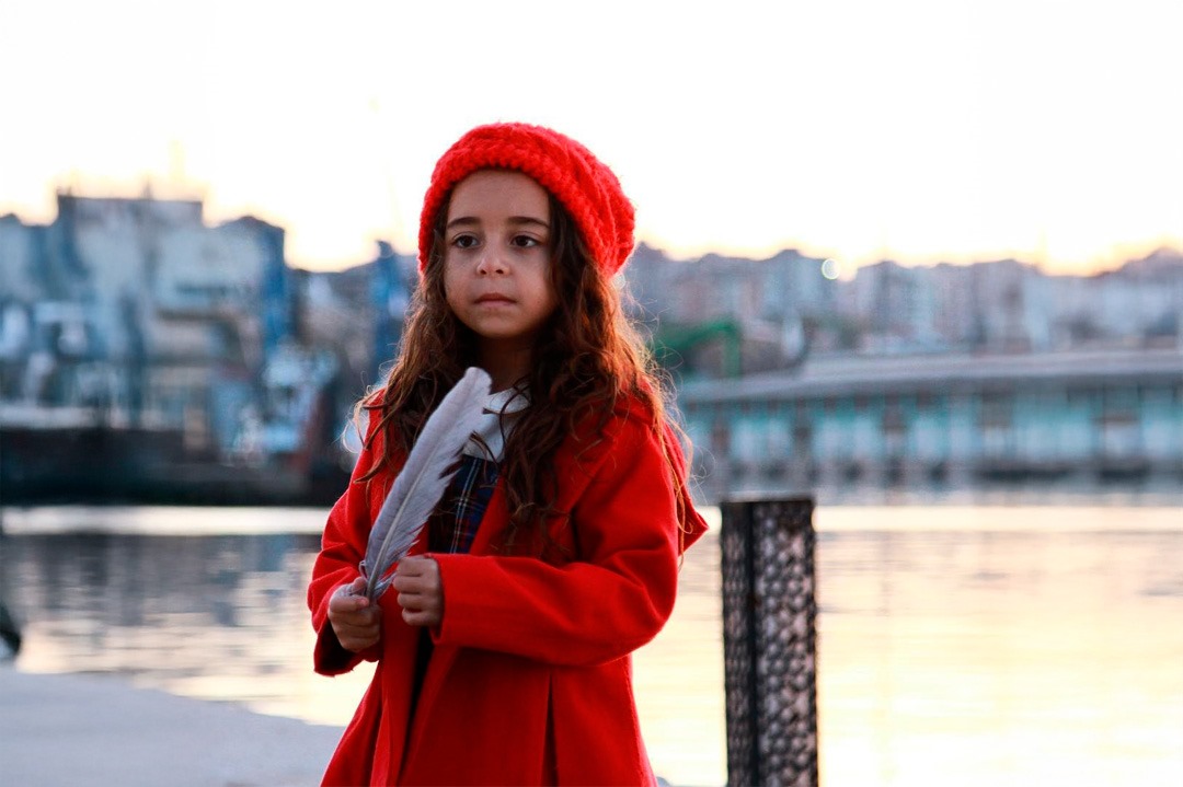 MELEK AKÇAY (Beren Gökyıldız) segura uma pena em frente a um lago em cena da novela Mãe