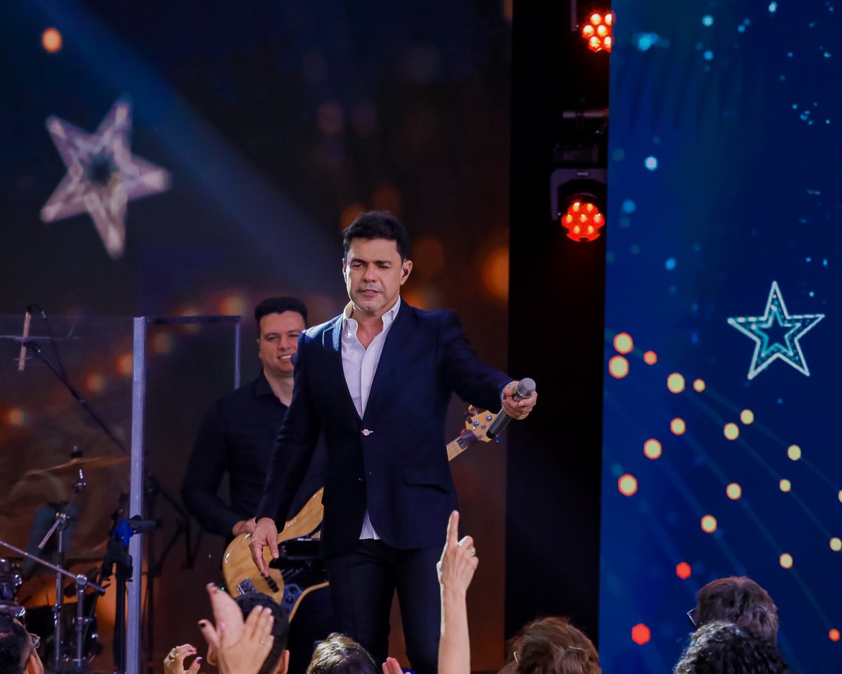 Zezé Di Camargo aponta o microfone para a plateia que assiste ao show especial de Natal no SBT