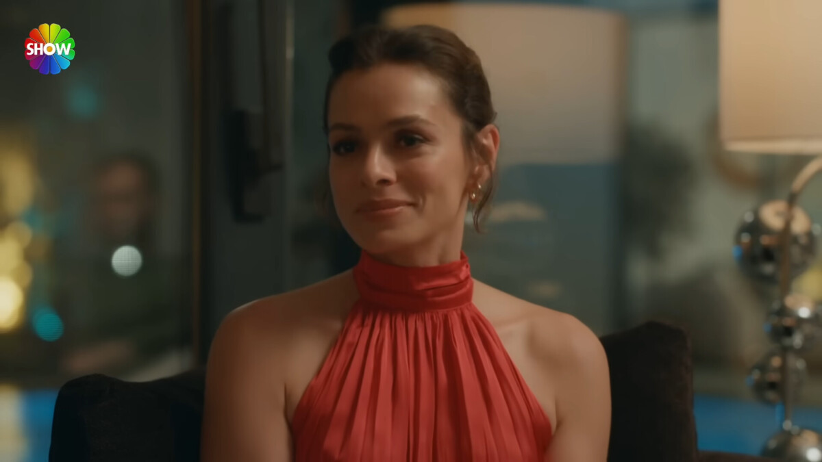 Özge Özpirinçci com vestido vermelho e sorridente em cena de 'I Am Mother'